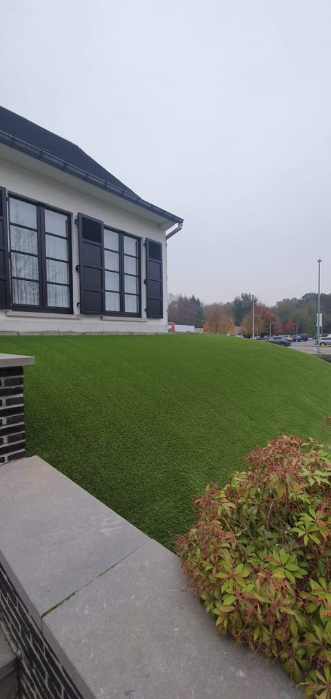 Kunstgras op een talud in de voortuin van een witte woning in Aalst
