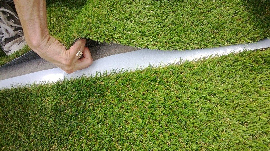Naadband wordt onder twee stroken kunstgras gelegd