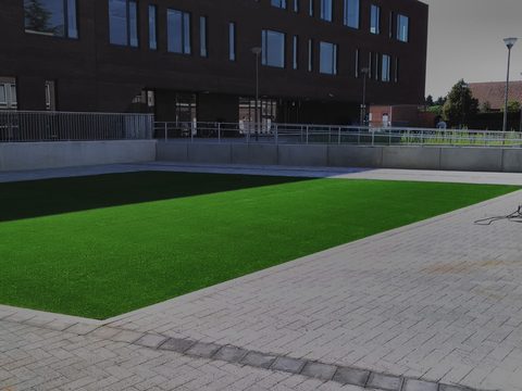 Groot plein met kunstgras aan een schoolgebouw in de provincie Antwerpen