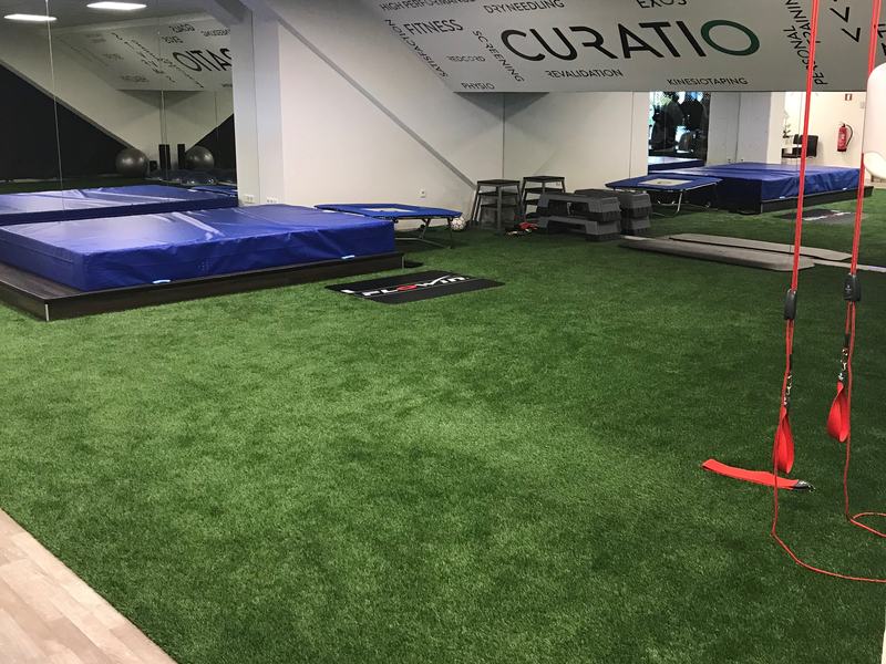 Oefenruimte van kinépraktijk Curatio in Balen met een vloer van kunstgras, valmatten en trainingsmateriaal