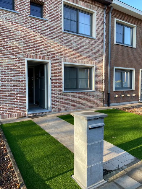 Voortuin met kunstgras en tegelpad bij een rijwoning in Beveren-Waas, gezien vanaf de straat