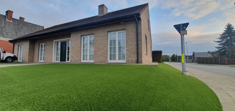 Ruime voortuin met kunstgras bij een villa in Blankenberge, langs de straat