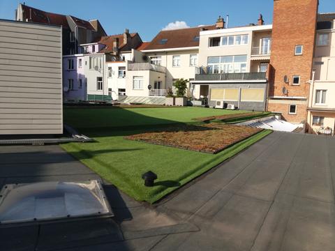 Gazon artificiel sur une toiture-terrasse entre les façades, à Bruxelles, pendant la pose
