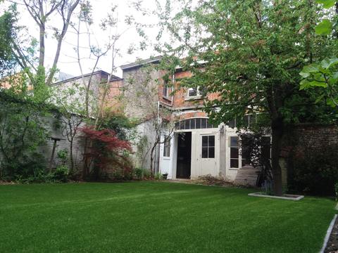 Jardin de ville clos de murs avec gazon artificiel derrière une maison de maître, à Bruxelles