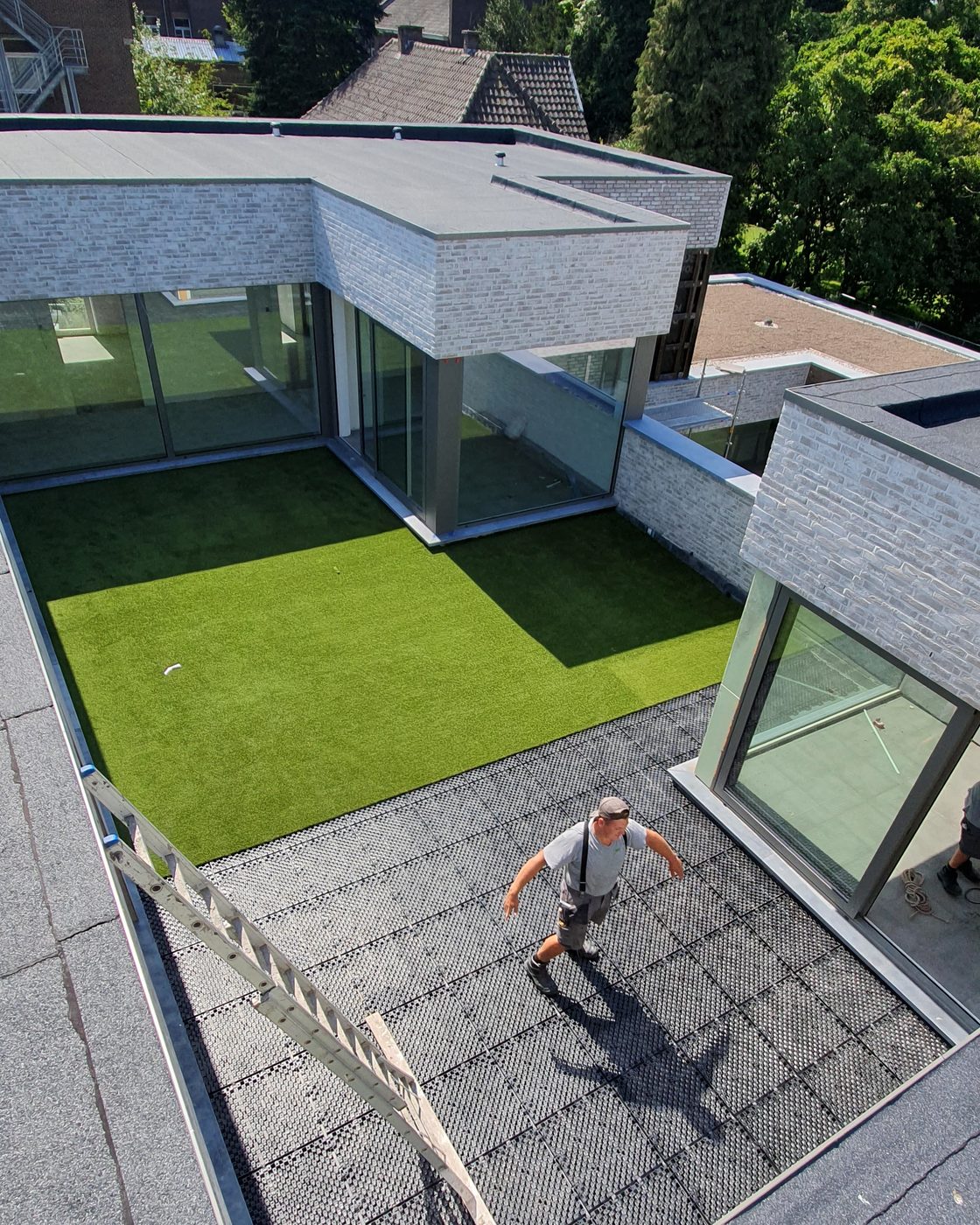 Dakterras in aanbouw: drainageplaten op de dakbedekking, met het kunstgras er deels op gelegd