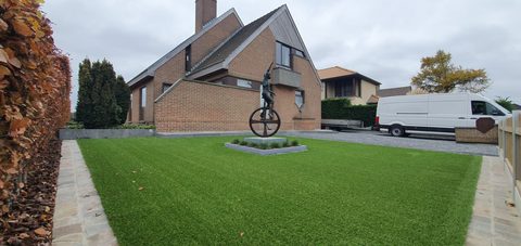 Voortuin met kunstgras rond een bronzen beeld bij een villa in Deinze