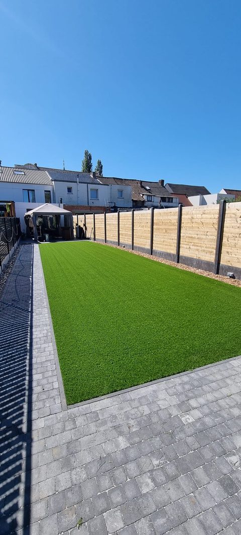 Smalle stadstuin in Erpe-Mere met kunstgras tussen klinkers, kiezelstrook en houten afsluiting