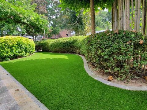 Kunstgras langs een oprit met hagen en beplanting