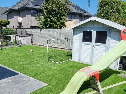 Speeltuin met kunstgras, glijbaan, tuinhuis en een voetbaldoel