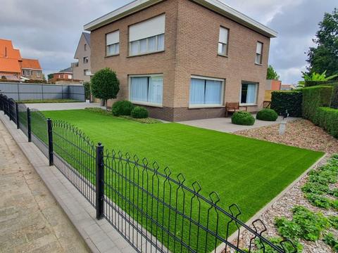 Voortuin met kunstgras achter een zwart sierhekje bij een woning in Evergem