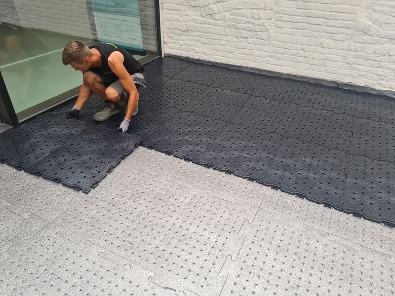 Plaatser klikt Future Base platen in elkaar op een dakterras, met de grijze antislipplaten ernaast