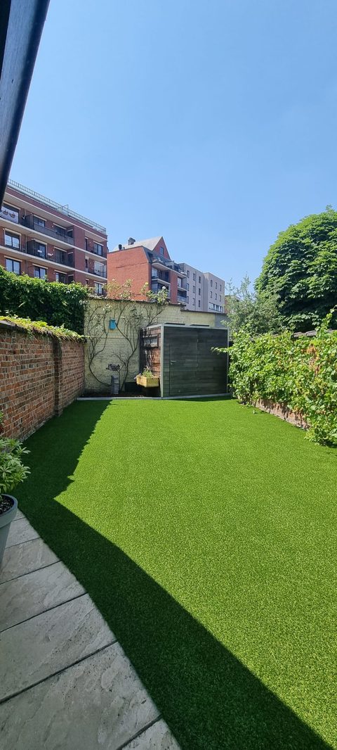 Stadstuin in Gent met kunstgras tussen bakstenen muren