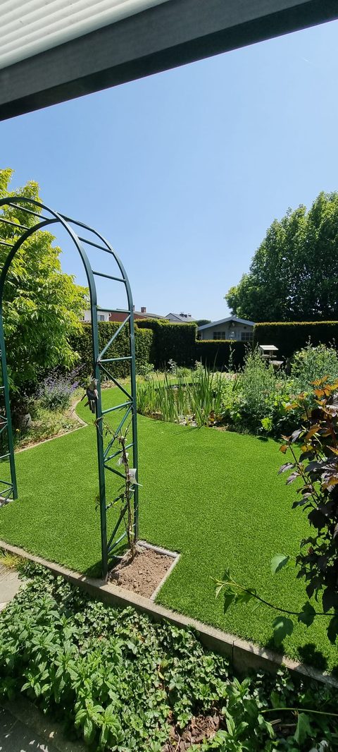 Tuin in Gent met kunstgras, vijver en rozenboog