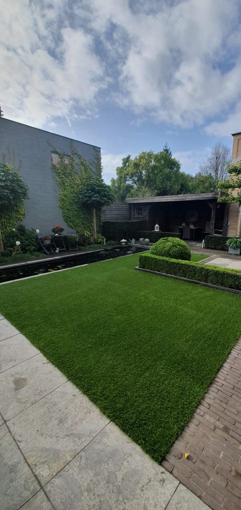 Stadstuin in Harelbeke met kunstgras naast een vijver
