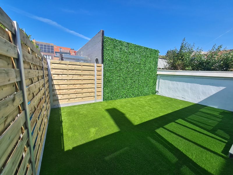 Stadskoer met kunstgras op de vloer en een groene kunstwand tegen de muur