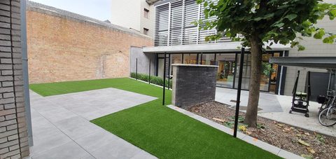 Tuin achter de nieuwe bibliotheek van Maldegem met kunstgras, terrastegels en een muurtje in zwarte baksteen