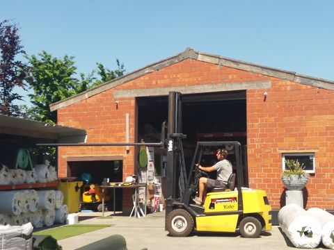 Een medewerker rijdt met de heftruck voor de loods van ForGrass in de Wildonkenstraat in Meigem