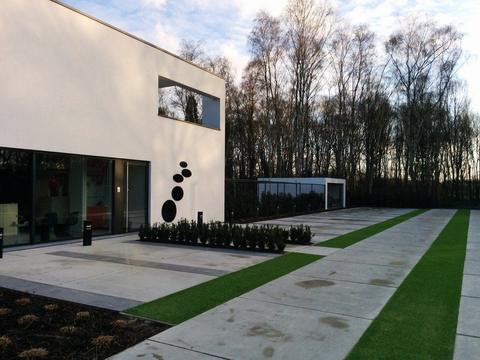 Jardin de façade avec gazon artificiel et revêtement devant une maison moderne, à Lovendegem
