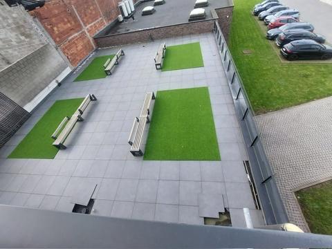 Dakterras met tegels en vier vlakken kunstgras met zitbanken, gezien van bovenaf