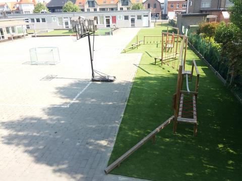 Schoolplein met een speelstrook in kunstgras naast de verharde speelplaats, met klimtoestellen en evenwichtsbalk