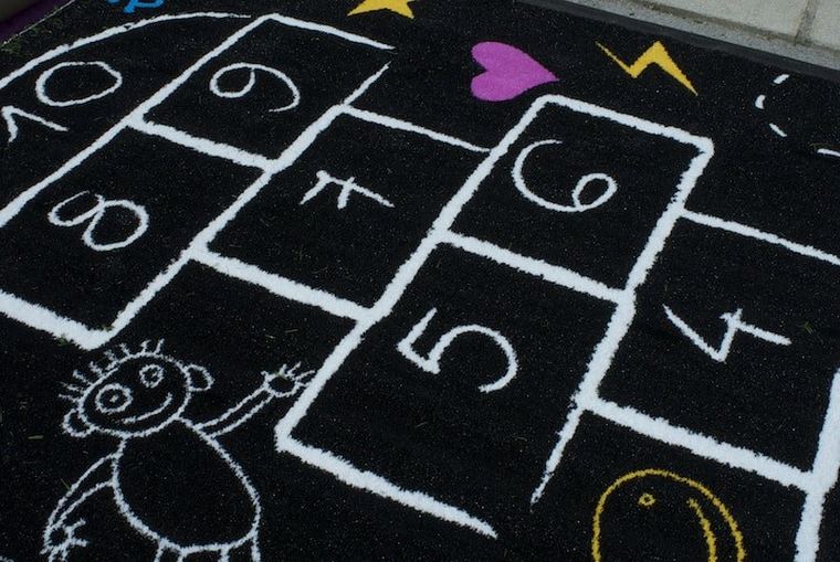 Hinkelspel ingelegd in kunstgras op een speelplaats