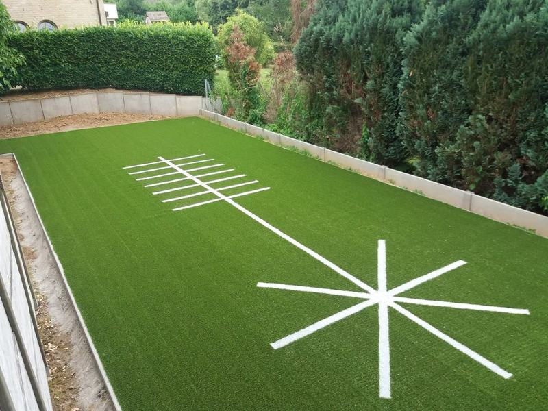 Oefenveld in kunstgras met witte ingelegde belijning in een tuin