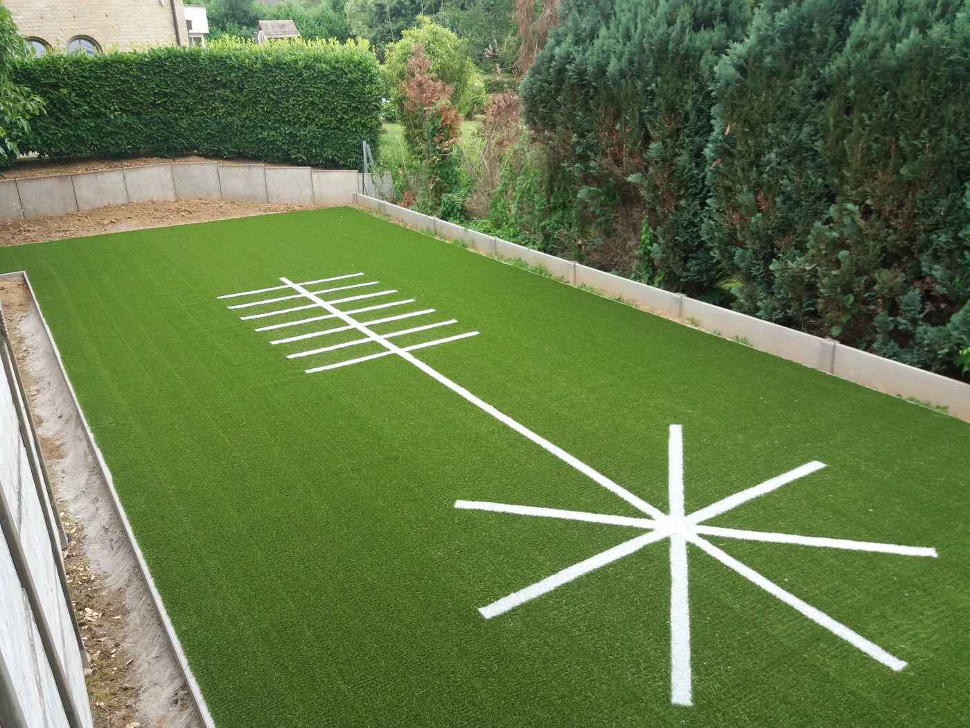 Oefenveld in kunstgras met witte ingelegde belijning in een tuin
