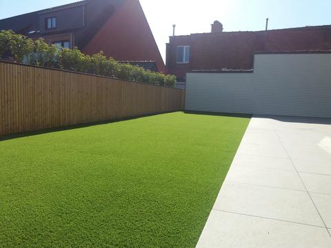 Dakterras in Torhout met kunstgras naast lichte tegels, omheind met een houten wand