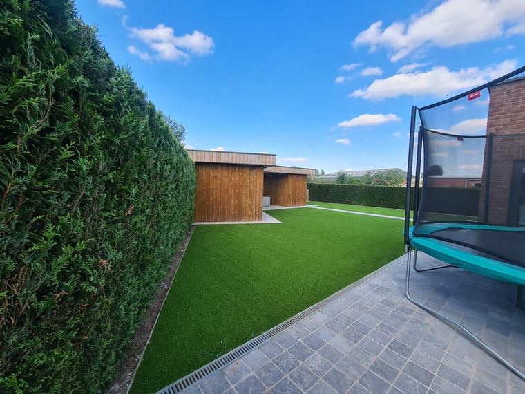 Gezinstuin met trampoline op kunstgras