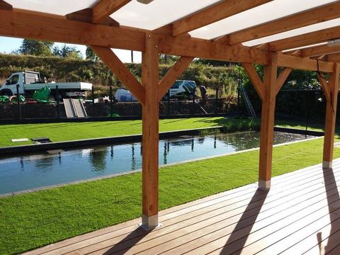 Gazon artificiel autour d&rsquo;un étang de baignade avec pergola en bois chez Blue Globe Sports, à Deinze