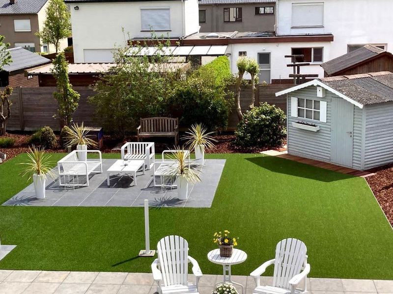 Jardin avec gazon artificiel, terrasse aménagée et abri de jardin