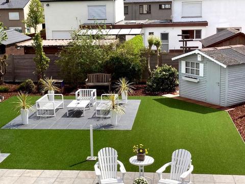 Jardin avec gazon artificiel, terrasse carrelée aménagée et abri de jardin