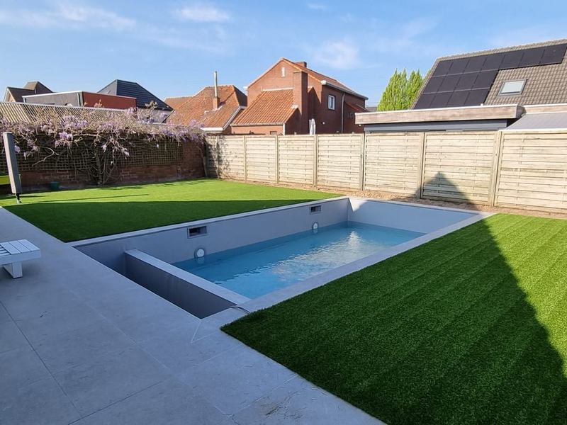 Zwembad met kunstgras eromheen in een tuin in de Leiestreek