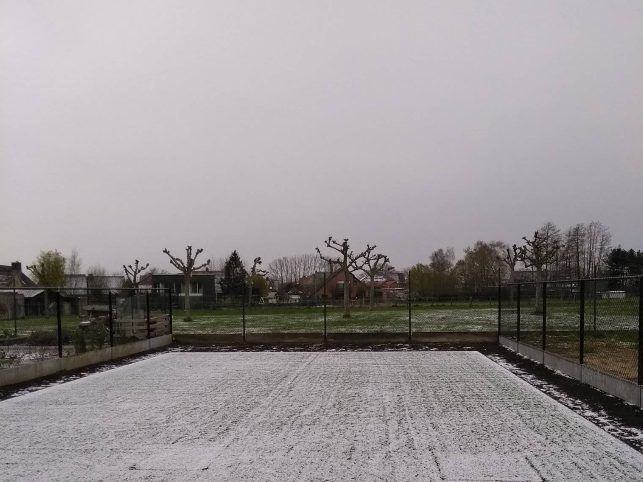 Vers gelegd kunstgras met een laagje sneeuw erop, in een winterse tuin