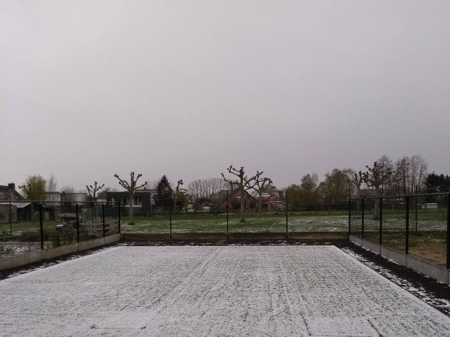 Vers gelegd kunstgras met een laagje sneeuw erop, in een winterse tuin