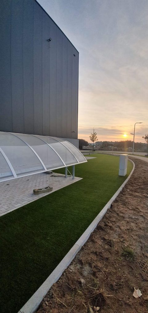 Kunstgras langs een bedrijfsgebouw in Zele bij zonsondergang