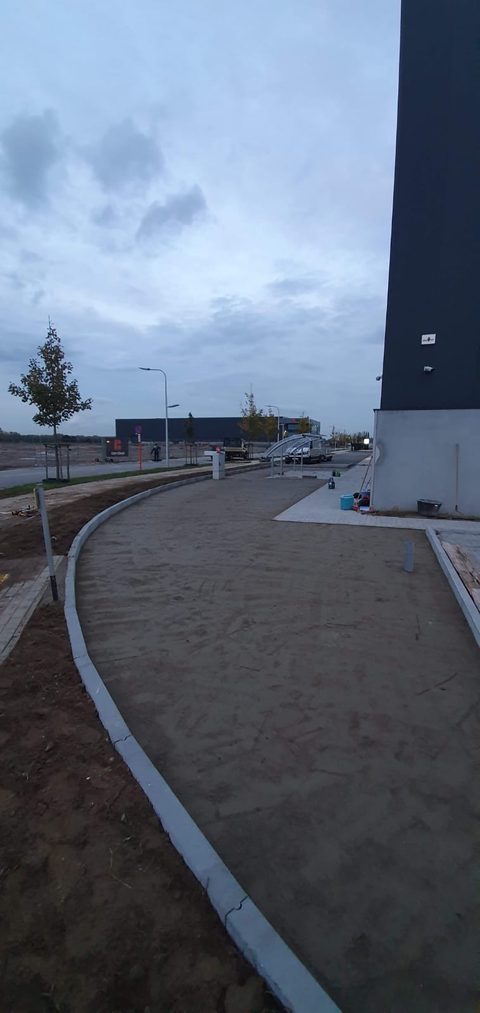 Verdichte funderingslaag van stabilisé tussen betonnen boordstenen, klaar voor het kunstgras, op een bedrijventerrein in Zele