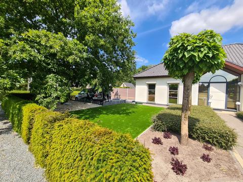 Jardin de façade avec gazon artificiel, catalpa boule et haies taillées, à Zelzate