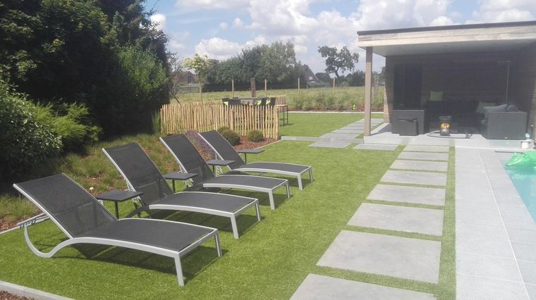 Tuin met ligbedden op kunstgras en een tuinberging